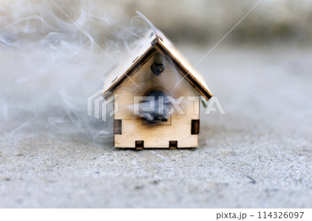 a toy wooden house is smoking. fire, disaster a toy wooden house is smoking. fire, disaster 114326097