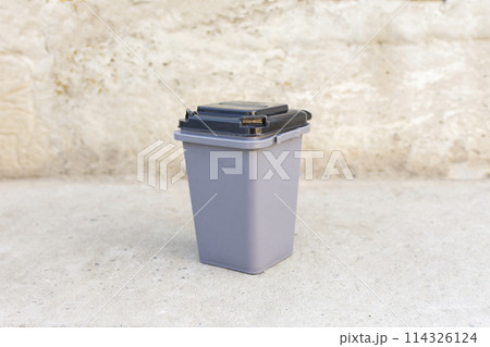 miniature plastic trash container on a gray concrete background 114326124