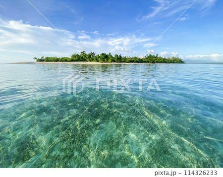 Beautiful small tropical island in the middle of the ocean against the backdrop of clear water and blue sky 114326233