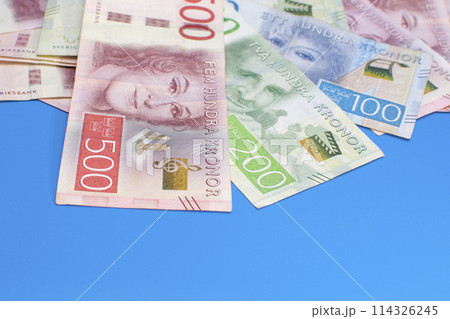 Swedish krona banknotes of different denominations on a blue background Swedish krona banknotes of different denominations on a blue background 114326245