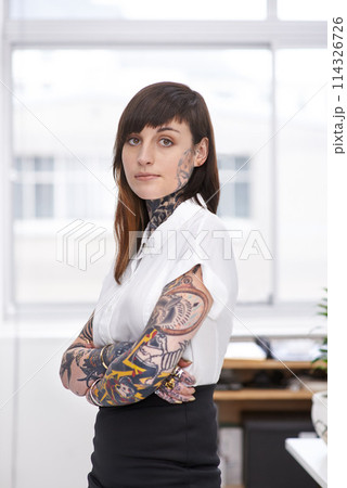 Tattoos, crossed arms and business woman in office with serious, pride and confident attitude. Grunge, professional and portrait of edgy creative designer with ink skin standing in modern workplace. 114326726