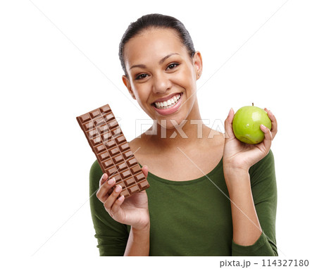 Portrait, happy woman and chocolate versus apple for health, wellness and diet benefits. Smile, person and choice of candy, fruits and organic food challenge for nutritional balance in studio 114327180