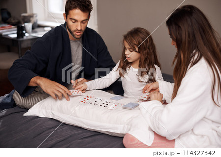 Parents, girl and fun with playing cards for game for bonding, learning and relax with strategy in bedroom. Father, mother and daughter with deal, maths and teaching with connection in family house 114327342