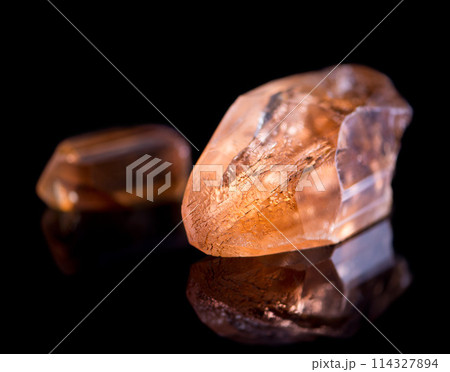 Orange stone, jewel and crystal in studio with isolated black background for natural resource, shine and sparkle for luxury. gemstone, rock and reflection in closeup for citrine, glow and mineral 114327894