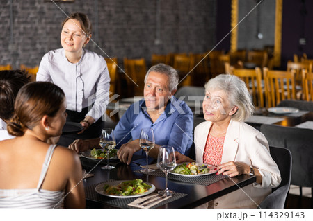 Female waiter serving wine to elderly couple and young couple in restaurant Female waiter serving wine to elderly couple and young couple in restaurant 114329143
