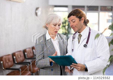Adult male doctor and elderly woman with documents folder Adult male doctor and elderly woman with documents folder 114329382
