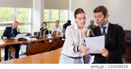 Middle aged white male manager discussing report with a young white subordinate female worker Middle aged white male manager discussing report with a young white subordinate female worker 114330019