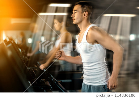 Man walk on treadmill in gym. Active hobby, extensive training Man walk on treadmill in gym. Active hobby, extensive training 114330100