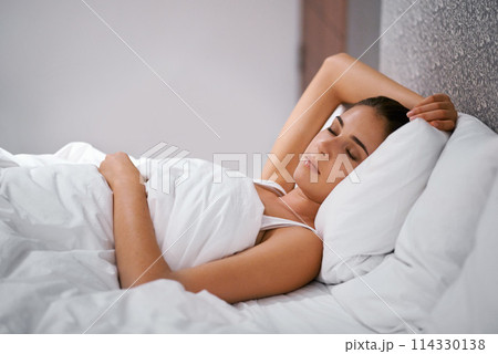 Bedroom, sleep and woman in bed at house, home and hotel to relax, rest and dreaming with duvet in Cape Town. Female person, lady and tired with pillow, blanket and eyes closed comfortable in nap 114330138