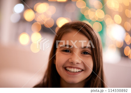Home, happy and portrait of child with in bedroom for relaxing, resting and calm at night. Youth, smile and face of young girl with fairy lights for childhood memories, positive and happiness 114330892
