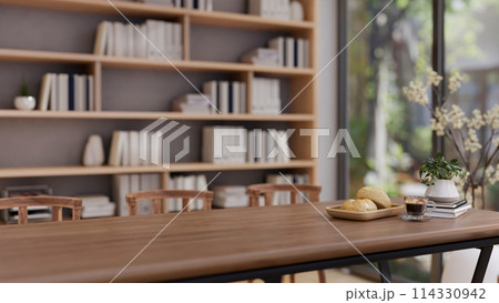 A wooden meeting table in a contemporary meeting room with a large bookshelf in the back. A wooden meeting table in a contemporary meeting room with a large bookshelf in the back. 114330942