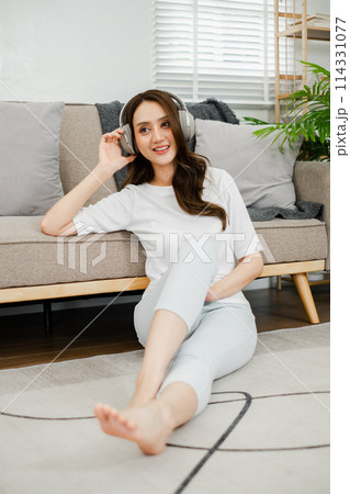 Young woman enjoys her favorite tunes, lounging comfortably on the floor at home with a stylish pair of headphones. Young woman enjoys her favorite tunes, lounging comfortably on the floor at home with a stylish pair of headphones. 114331077