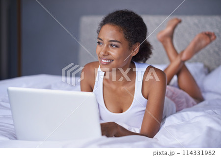 Black woman, laptop or bed to relax as thinking of idea for social media, post, blog or meme. Female writer, lying or computer as planning, vision or daydreaming of viral news to search online 114331982