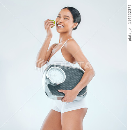 Health, scale and portrait of woman for diet, apple and nutrition on white background. Weight loss, food and vitamins or fruit for fibre and wellness, benefits and studio and female model or athlete 114332375