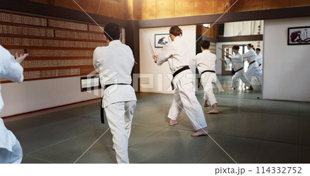 Aikido group, fight and bokken of martial arts, weapon or black back students at training, gym or dojo. Japanese people, wood sword and club for exercise, workout or fitness in conflict with battle 114332752