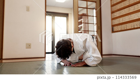 Aikido student, man or bow in dojo for training practice, discipline and black belt in class. Respect, greeting and Japanese person on floor with traditional gesture, culture and martial arts in gym. 114333569