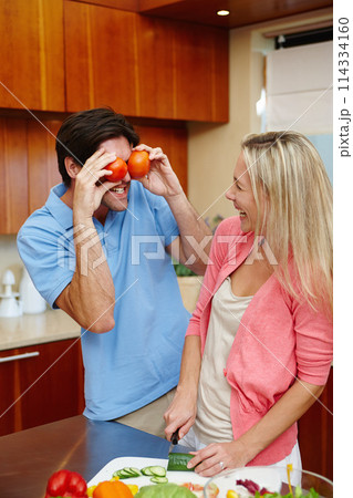 Happy, man and woman in cooking, smile and playful in kitchen at home for dinner, plans and family. Married couple in preparing, food or salad for healthy, eating and nutrition in house with tomatoes 114334160