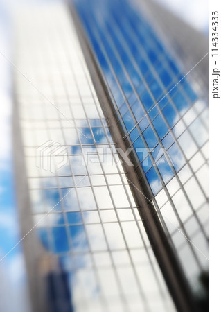 Blurry, building and window of skyscraper in city with reflection of blue sky and clouds on glass. Urban, office and architecture of tower or hotel with trippy motion for vertigo from heights in town 114334333