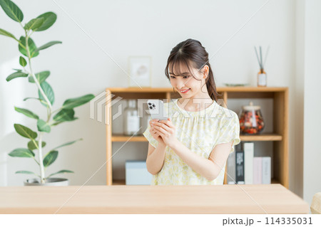リビングでスマホを操作する女性。 リビングでスマホを操作する女性。 114335031