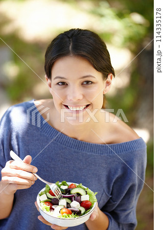 Portrait, woman and salad in outdoor for diet, nutrition and healthy eating. Green vegetables, vegan and face of happy female person in garden for detox with organic food, vitamins and wellbeing 114335178