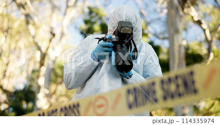Csi, photographer and police tape at crime scene for investigation in forest with evidence and safety hazmat..Forensic quarantine, expert investigator and pictures for observation and case research 114335974