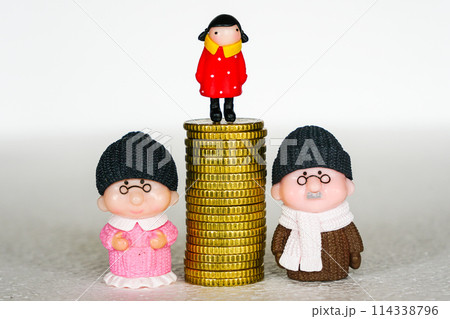 Between mother and father toy figures pile of coins with a child on it, concept of inheritance 114338796