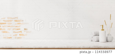 A minimal white tabletop with towels, a shampoo bottle, and display space against the brick wall. A minimal white tabletop with towels, a shampoo bottle, and display space against the brick wall. 114338977