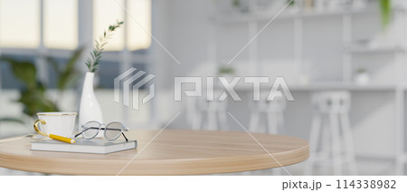 A close-up image of a minimal round wooden table in a modern white cafe. A close-up image of a minimal round wooden table in a modern white cafe. 114338982
