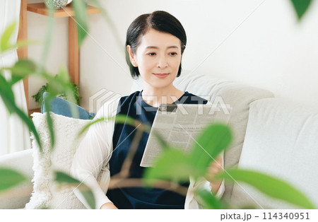 リビングで英字新聞を読む女性 リビングで英字新聞を読む女性 114340951
