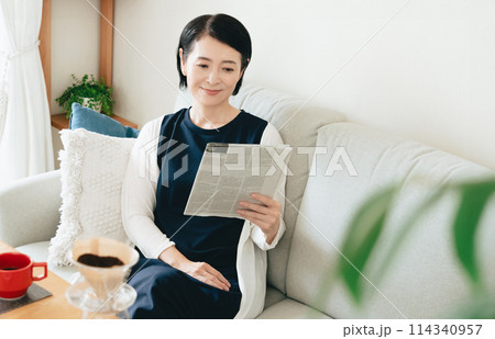 リビングで英字新聞を読む女性 114340957