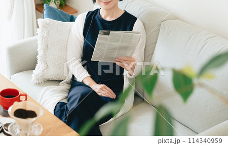 リビングで英字新聞を読む女性 114340959