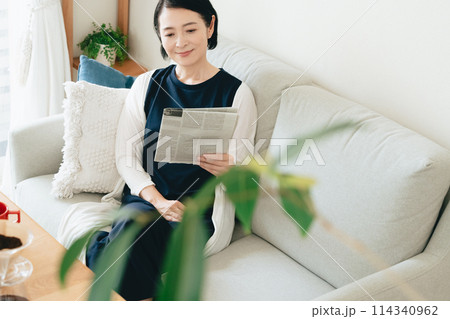 リビングで英字新聞を読む女性 リビングで英字新聞を読む女性 114340962