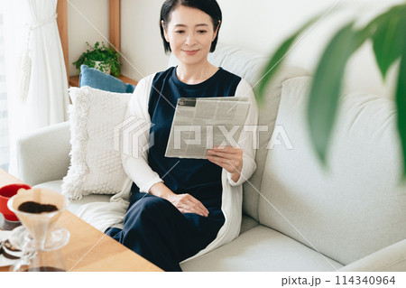リビングで英字新聞を読む女性 リビングで英字新聞を読む女性 114340964