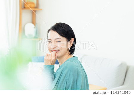 リビングでハーブティーを飲むミドル女性 114341040