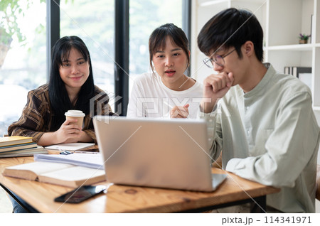 A group of Asian university students is discussing work in a co-working space. 114341971