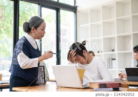 Young student struggle to understand the lesson while teacher trying to help her in the classroom. Young student struggle to understand the lesson while teacher trying to help her in the classroom. 114342052