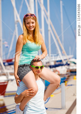 Man giving girlfriend piggyback ride on marina Man giving girlfriend piggyback ride on marina 114343086