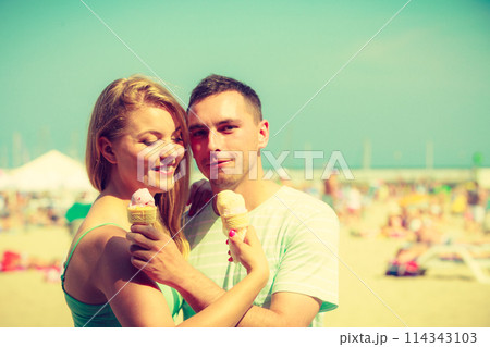 Man and woman eating ice cream on beach 114343103
