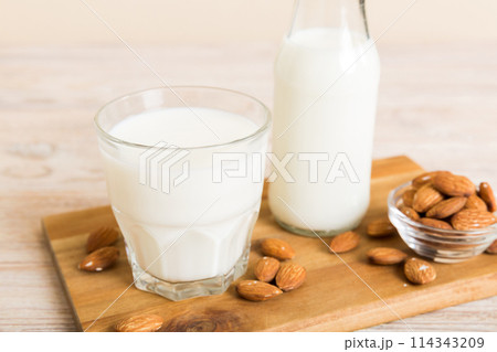 Top view of the almond milk in the glass bottle with almond nuts on the colored table. top view vith copy space Top view of the almond milk in the glass bottle with almond nuts on the colored table. top view vith copy space 114343209