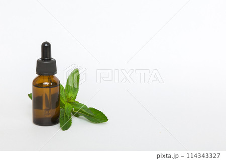 Natural Mint Essential Oil in a Glass Bottle. organic cosmetics with herbal extracts of mint on colored background Natural Mint Essential Oil in a Glass Bottle. organic cosmetics with herbal extracts of mint on colored background 114343327