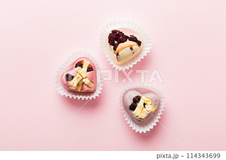 chocolate sweets in the form of a heart with fruits and nuts on a colored background. top view with space for text, holiday concept 114343699