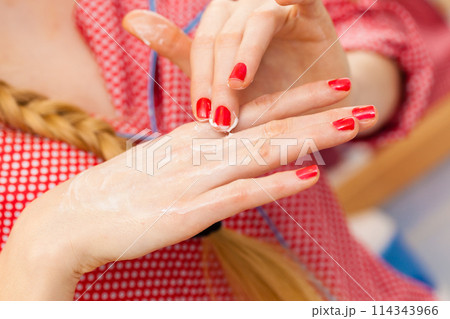 Woman applying hand cream on hands 114343966