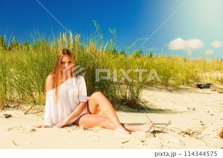 Young woman posing in grassy dune 114344575