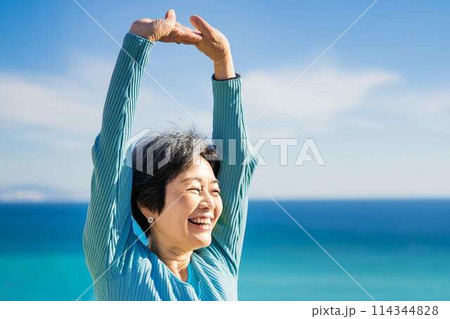 海を背景にストレッチをするシニア女性 114344828
