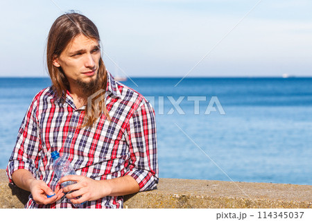 Man long hair relaxing by seaside drinking water 114345037