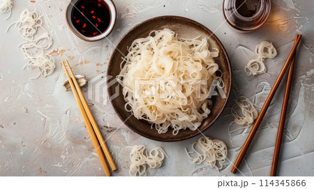 Shirataki noodles in bowl with chopsticks and soy sauce on stone background Shirataki noodles in bowl with chopsticks and soy sauce on stone background 114345866