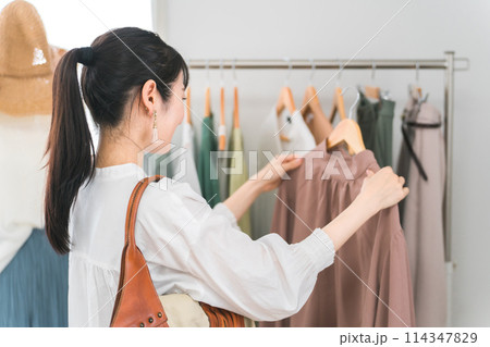 アパレルショップで洋服を買い物・ショッピングする女性 アパレルショップで洋服を買い物・ショッピングする女性 114347829