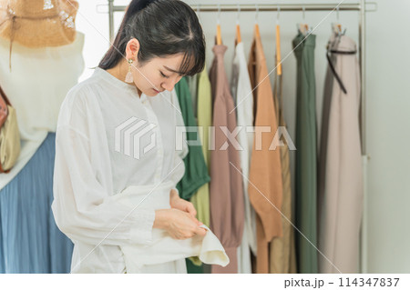 服を畳むショップ・服屋で働く販売員・従業員・ショップ店員のアジア人女性 114347837