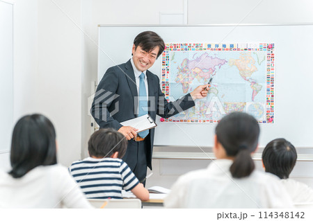 塾・学校の教室で小学生・中学生の子供に勉強を教える男性講師・教師 塾・学校の教室で小学生・中学生の子供に勉強を教える男性講師・教師 114348142