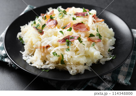 Slovak potato dumplings halusky with steamed sauerkraut and bacon on black background 114348800